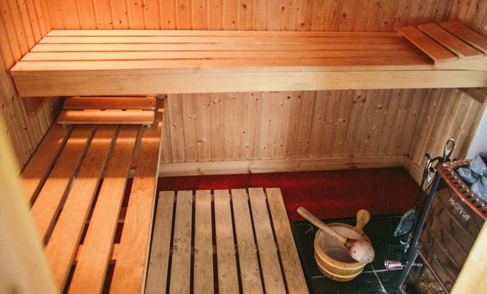 The first sauna in a shepherd's hut - wood-burning sauna stove with 2 benches for sitting on and a wooden bucket and ladle for pouring water on the sa